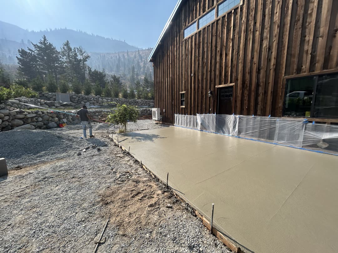 Large concrete flatwork pour at a timber-clad barn with Cascade mountains in the background
