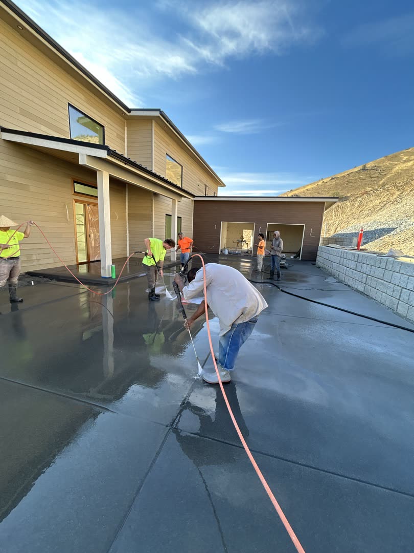 Crew finishing a freshly poured concrete driveway at a hillside home