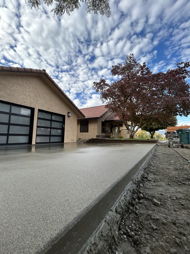 Exposed aggregate driveway curving up to a residential garage under a cloudy sky